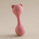 Pink silicone baby rattle with bear ears on a beige background