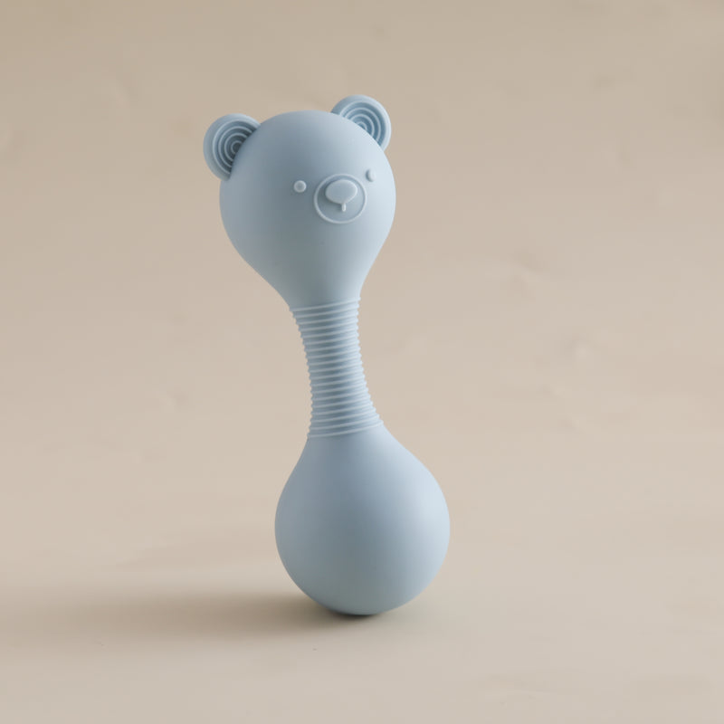 Blue bear-shaped rattle on a beige background