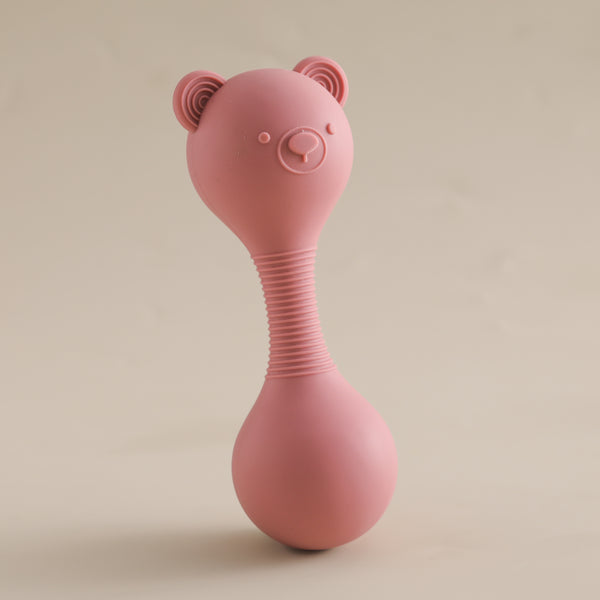 Pink silicone baby rattle with bear ears on a beige background