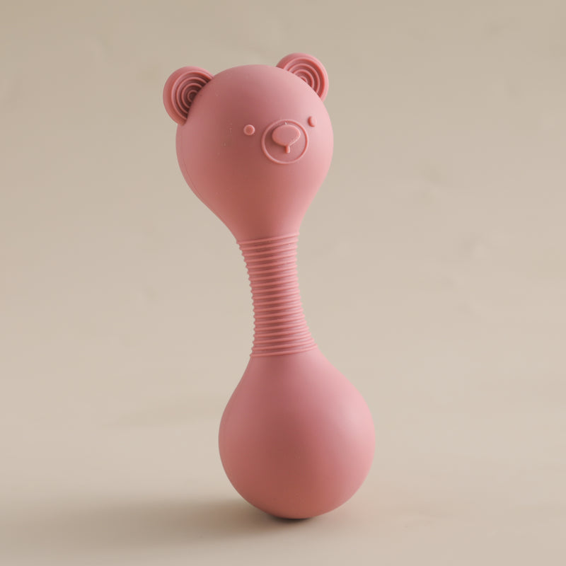 Pink silicone baby rattle with bear ears on a beige background